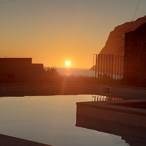 a sunset over a body of water with the sun setting at Maria's House in Câmara de Lobos