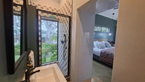 a bathroom with a sink and a bedroom with a bed at Pond Cottage in Knysna