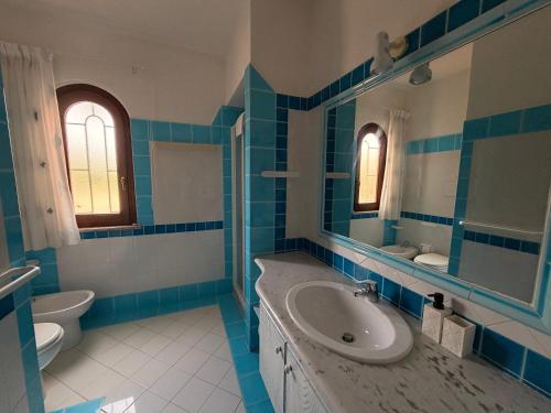 a blue and white bathroom with a sink and a toilet at Villa Pinna in San Teodoro