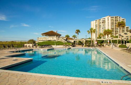 a large pool with blue water in front of a building at Ocean Creek Resort in Myrtle Beach