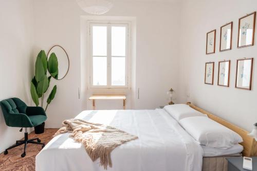 a white bedroom with a bed and a green chair at Panoramic Stone Retreat - Menaggio by LoveComo in Menaggio
