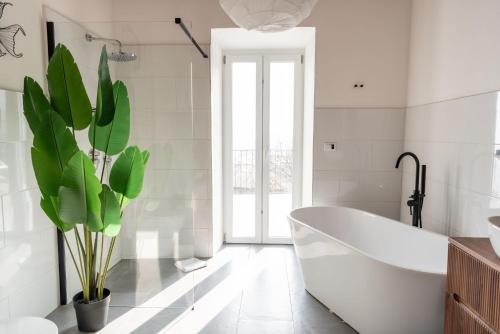a white bathroom with a tub and a plant at Panoramic Stone Retreat - Menaggio by LoveComo in Menaggio