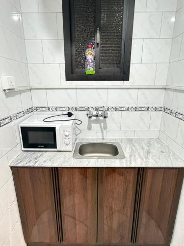 a kitchen counter with a microwave and a sink at فندق صفوة الجميزة in An Naqāʼ