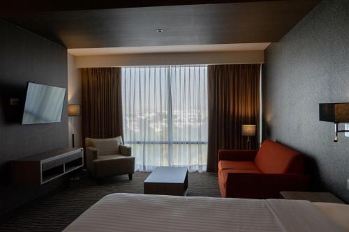 a hotel room with a bed and a couch and a window at Hilton Garden Inn Leon Poliforum in León