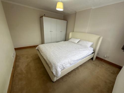 a bedroom with a bed and a cabinet in it at Spacious 3 bed semi-detached house in Luton