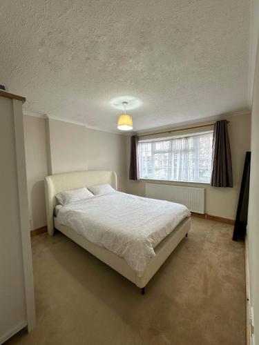 a bedroom with a large bed and a window at Spacious 3 bed semi-detached house in Luton