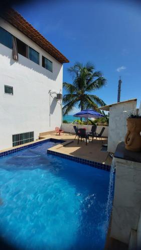 a swimming pool next to a house with a palm tree at Casa Maragogi 6 Quartos E Piscina in Maragogi