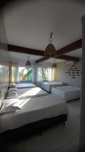a large bedroom with three beds and two windows at Casa Maragogi 6 Quartos E Piscina in Maragogi