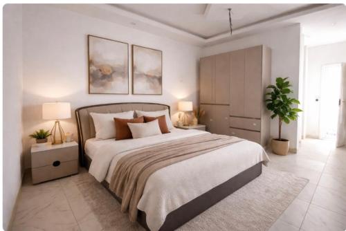 Ein weißes Schlafzimmer mit einem großen Bett und zwei Lampen in der Unterkunft Residence BASI - Appartement 2 chambres in Rufisque