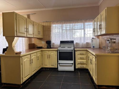 a kitchen with yellow cabinets and a stove top oven at Amatis House in Mokopane