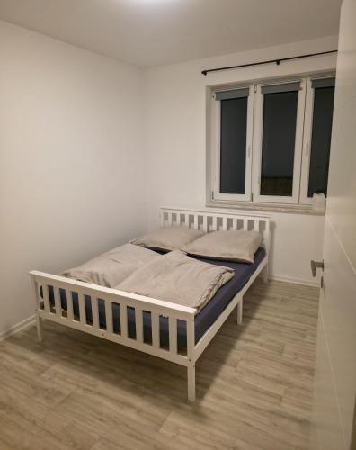 a bed in a white room with a window at Weserblick Apartment Stolzenau 24h Selfcheckin in Stolzenau