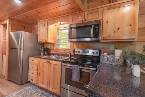 a kitchen with stainless steel appliances and wooden cabinets at Ryon Tiny Home Cabin City-side Rustic Retreat in Chattanooga