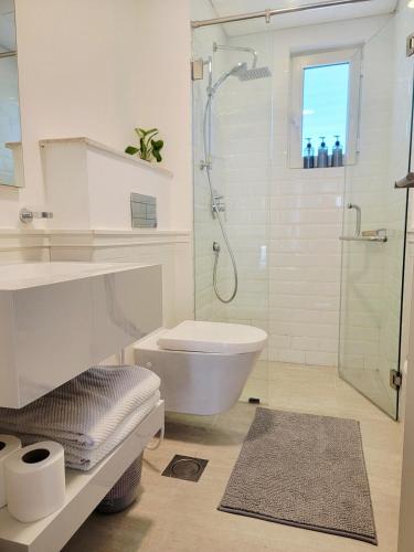 a white bathroom with a shower and a toilet at Manzar View - Private Rooftop Dining & Epic Views in As Sīfah