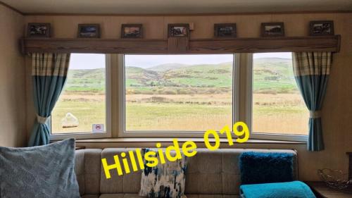 a living room with a large window with a view of a field at Lyons Sunnysands - Hillside 019 in Barmouth