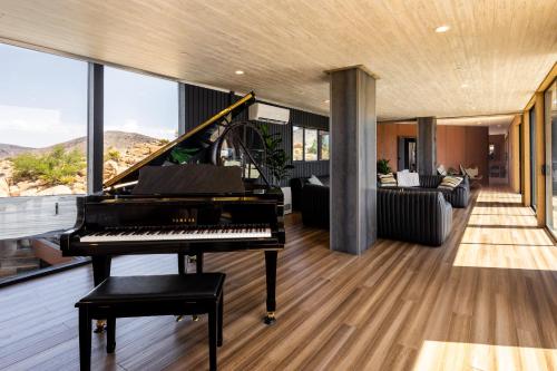 a living room with a piano and a couch at Iconic 7,000sf Glass Villa with 2 Pools on 350 Acres in Pioneertown