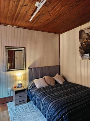 a bedroom with a bed and a table with a night stand at Puerto sureño in Puerto Montt