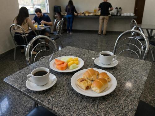 two cups of coffee and plates of food on a table at Hotel Royal - Rubiataba in Rubiataba
