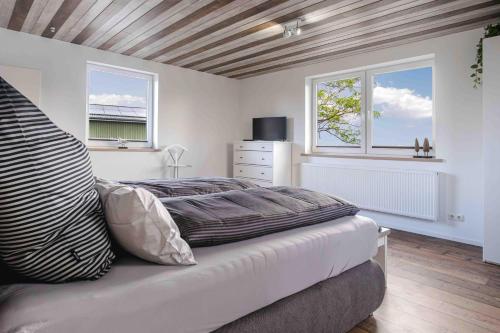 a bedroom with a bed and two windows at Haus Sonnengelb in Taarstedt