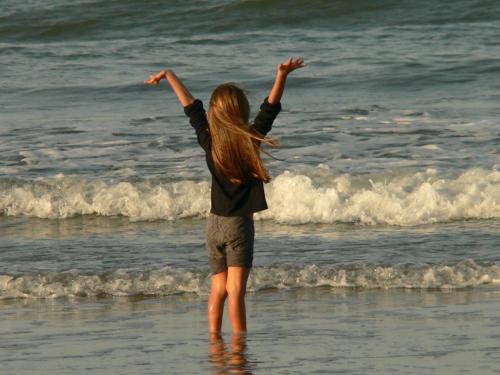 a woman standing on the beach with her arms in the water at ESPECTACULAR Alem 5007 piso 7 in Mar del Plata