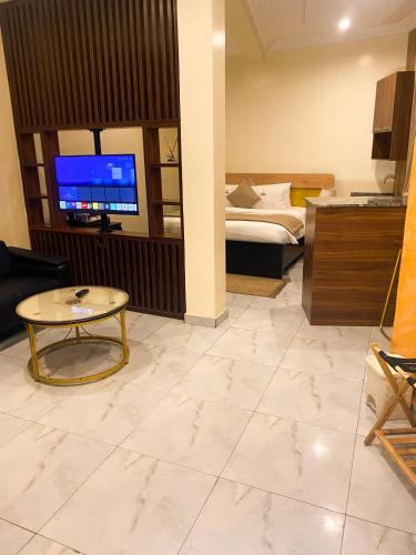 ein Wohnzimmer mit Fernseher, Bett und Tisch in der Unterkunft Providha Hotel & Suites in Ikeja