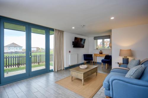 a living room with a blue couch and a table at Le Strange Arms Garden Lodges in Hunstanton