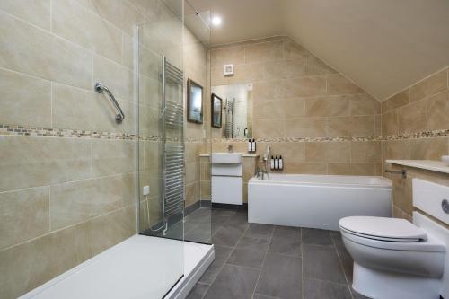 a bathroom with a tub and a toilet and a sink at Le Strange Arms Garden Lodges in Hunstanton