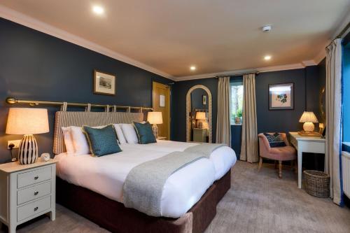 a bedroom with a large bed with blue walls at Le Strange Arms Garden Lodges in Hunstanton