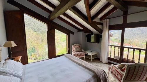 a bedroom with a large bed and large windows at Posada El Bosque in Mieses