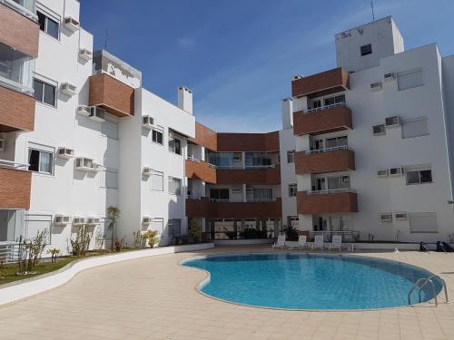 a swimming pool in front of a building at Apto de 02 qtos no Ingleses - Florianopolis - SC in Florianópolis