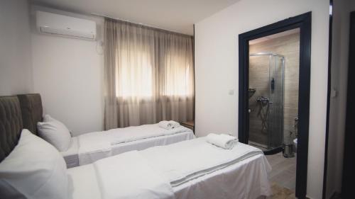 two beds in a room with a shower and a mirror at Saint Sava in Ohrid