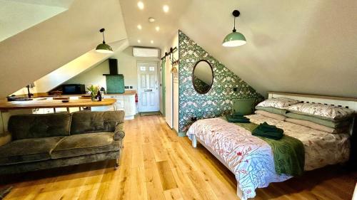 a bedroom with a bed and a couch and a kitchen at The Coach House in Torpoint