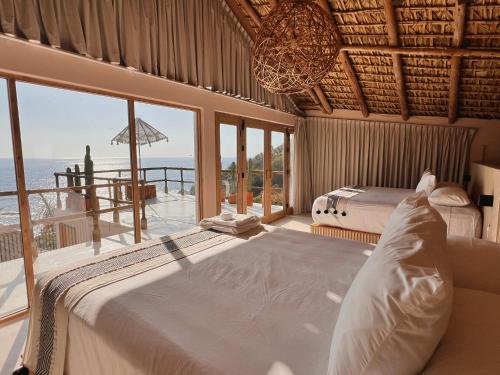 ein Schlafzimmer mit zwei Betten und Meerblick in der Unterkunft Xeno Hotel Boutique in Playa Estacahuite