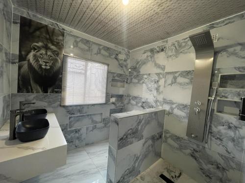 a bathroom with a lion painting on the wall at Alamaison in Umtali