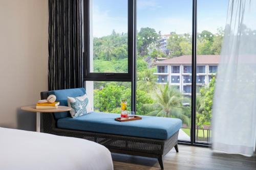 ein Hotelzimmer mit einem Bett und einem großen Fenster in der Unterkunft OZO Phuket in Kata Beach