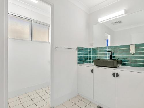 a bathroom with white cabinets and a sink at Bentleigh Motor Inn - Coffs Harbour in Coffs Harbour