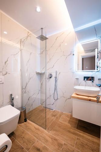 a bathroom with a shower and a toilet and a sink at Velora Apartments Ksamil in Ksamil