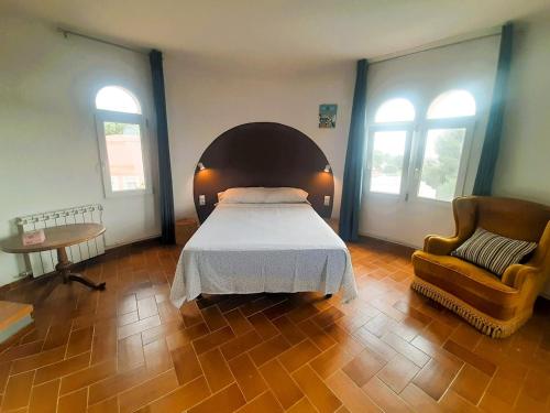 a bedroom with a bed and a chair and two windows at Villa Gigi Torre del Sol - 14-18 pers - Coma-Ruga in El Vendrell