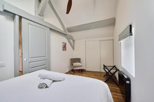 a bedroom with a white bed with a towel on it at Le Bossuet - Cosy et Charme au Centre Historique in Dijon