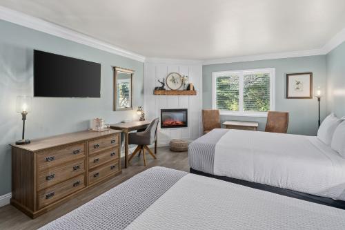 a bedroom with two beds and a desk and a fireplace at Cambria Pines Lodge in Cambria