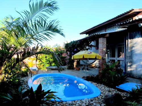 a swimming pool in a yard with an umbrella at Pousada Villa da Nascente in Florianópolis