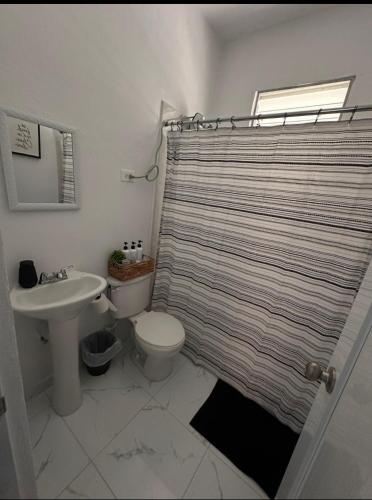 a bathroom with a toilet and a shower curtain at La Casita del Este in Fajardo