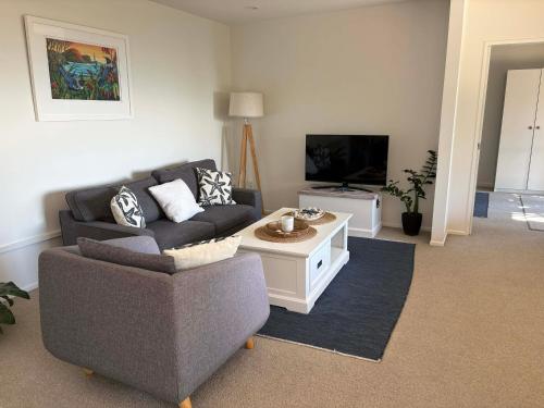 a living room with a couch and a tv at The Beach House in Red Beach