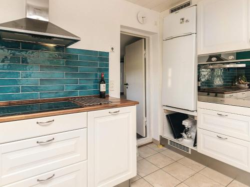 a kitchen with white cabinets and a bottle of wine at 6 person holiday home in Humble-By Traum in Humble