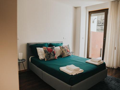 a bed with green sheets and pillows in a room at Casa Moinho Vedro in Quintiães