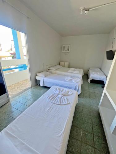 two beds in a room with a balcony at Pousada Valmar in Aracaju