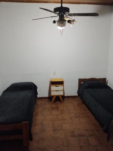 two beds in a room with a ceiling fan at Refugio Pampa - General Pico in General Pico