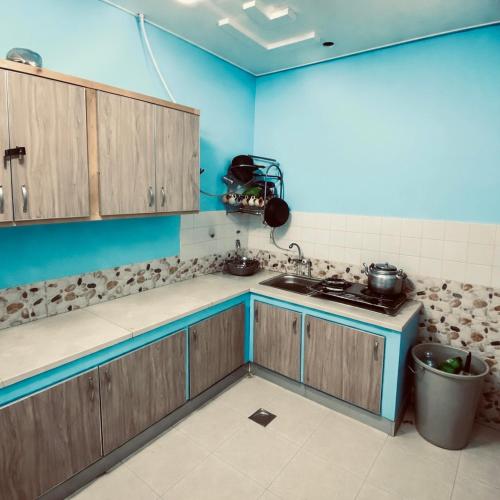 a kitchen with blue walls and wooden cabinets at Getaway lodge Guesthouse in Islamabad