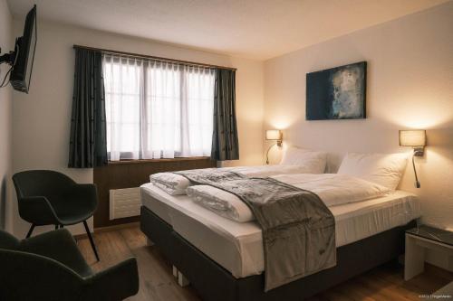 a bedroom with a bed with a chair and a window at Gasthof Tenne - Ferie mit Härz in Lenk