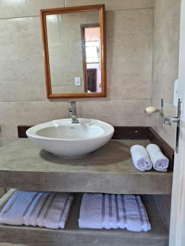 a bathroom with a sink and a mirror and towels at Cozy, rustic apartment with balcony in Búzios