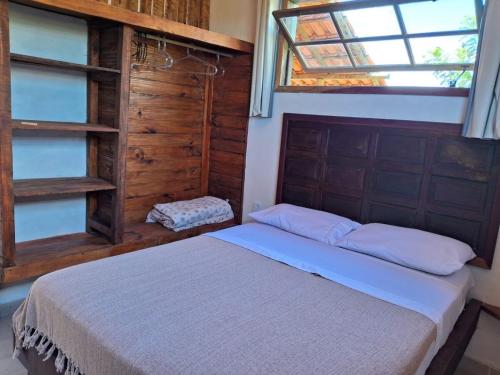 a bedroom with a bed in a room with a window at Cozy, rustic apartment with balcony in Búzios